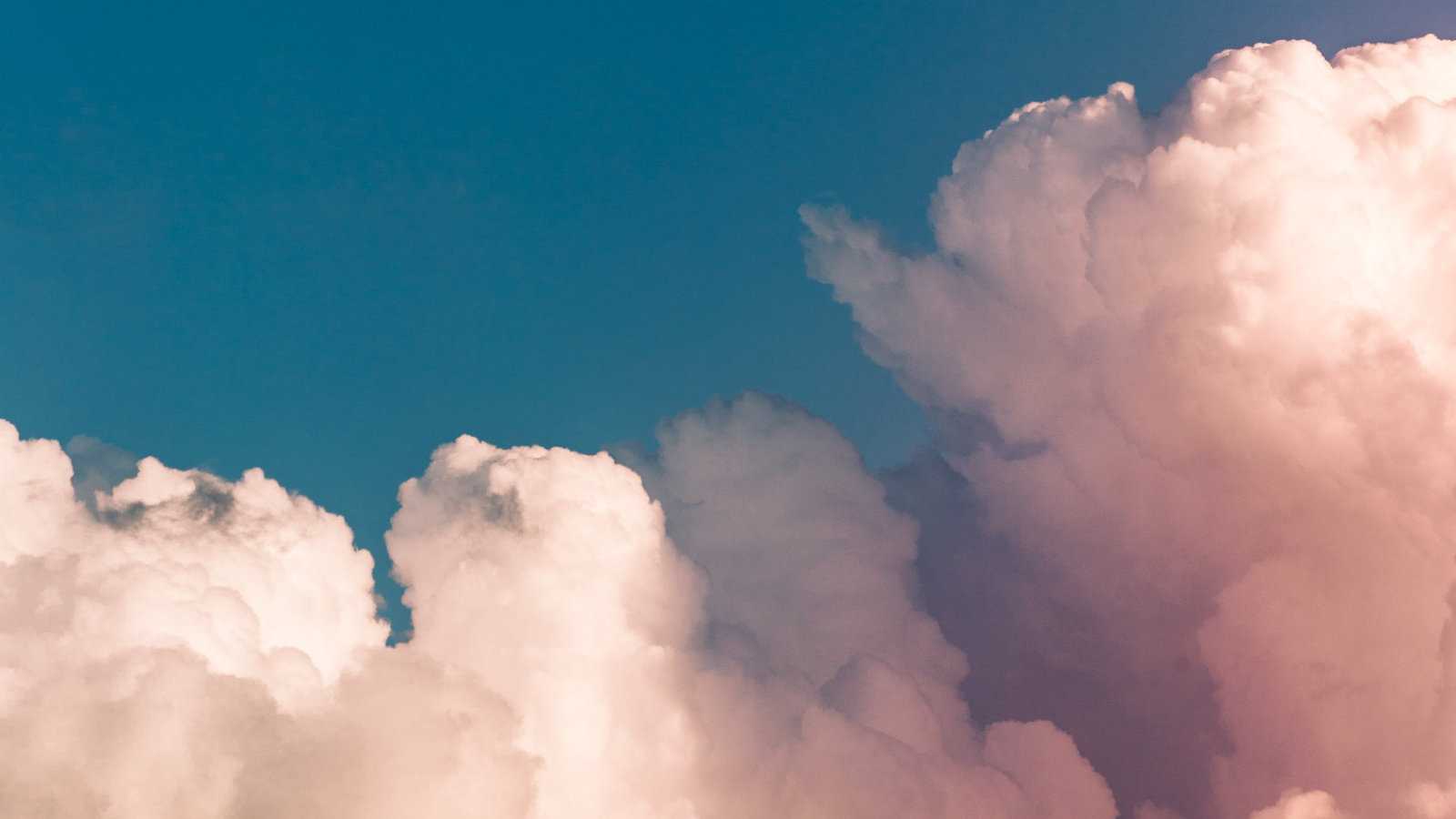 Blauer Himmel mit rosa Wolken, symbolisiert Gelassenheit und innere Ruhe für verbessertes Wohlbefinden.