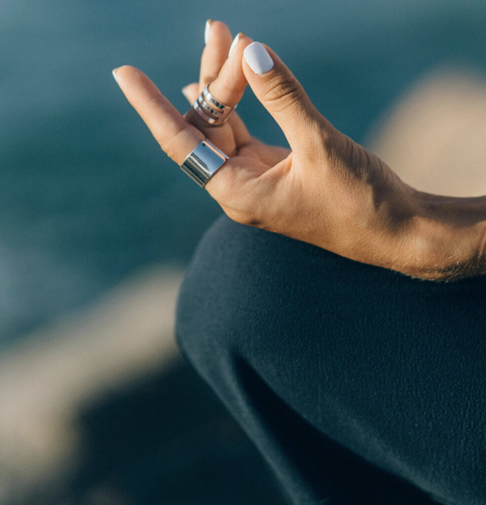Ein Close-up einer Hand, die ein Mudra-Geste formt, eine Handhaltung, die im Yoga und der Meditation für das Wohlbefinden verwendet wird. Die Finger sind in einer bestimmten Position angeordnet, um Energie zu kanalisieren und innere Ausgeglichenheit zu fördern.